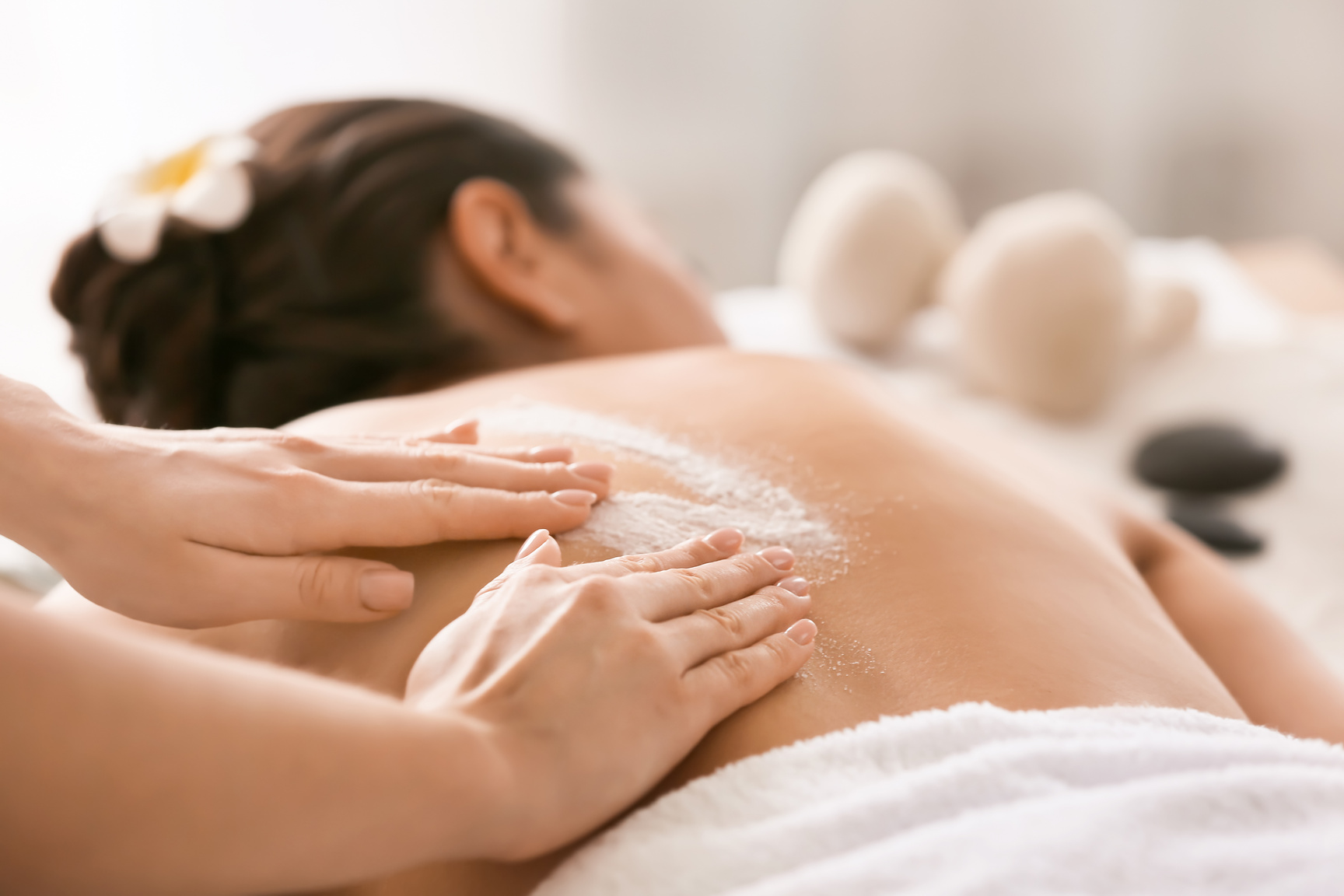 Young Woman Undergoing Treatment with Body Scrub in Spa Salon